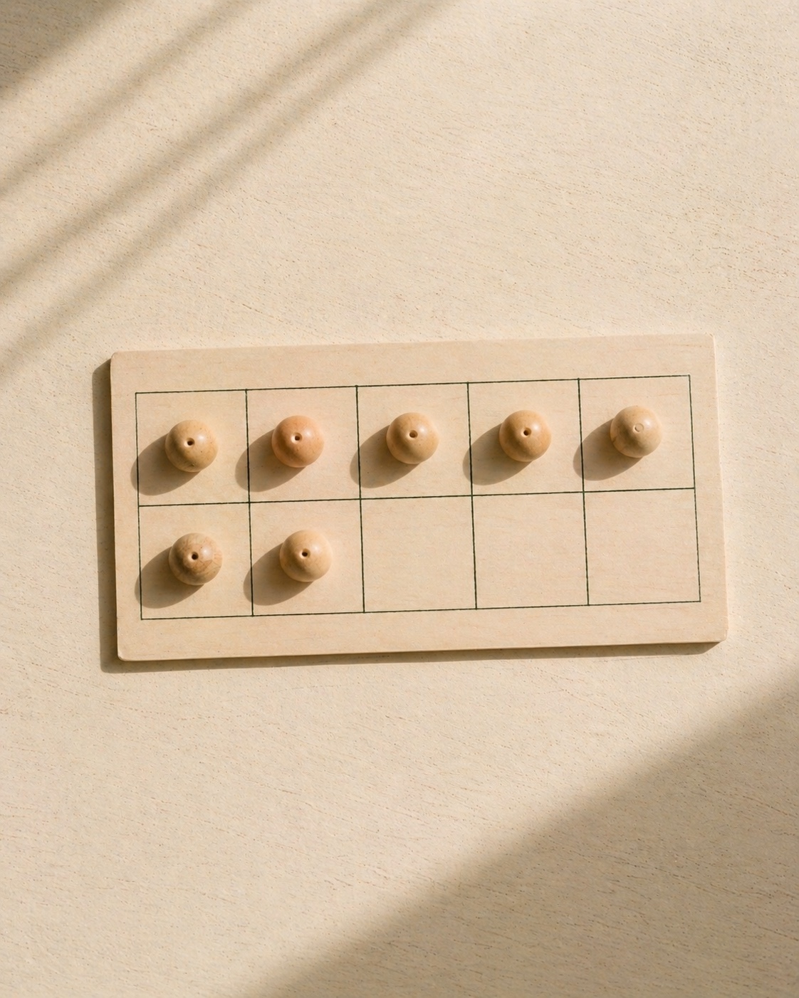 A ten-frame with wooden counters, half full.